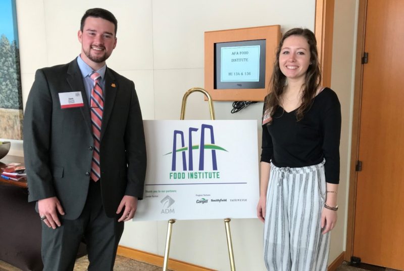 Zach Jacobs and Margaret Benson stand next to an AFA sign at the 2019 Agriculture Future of America Food Institute.
