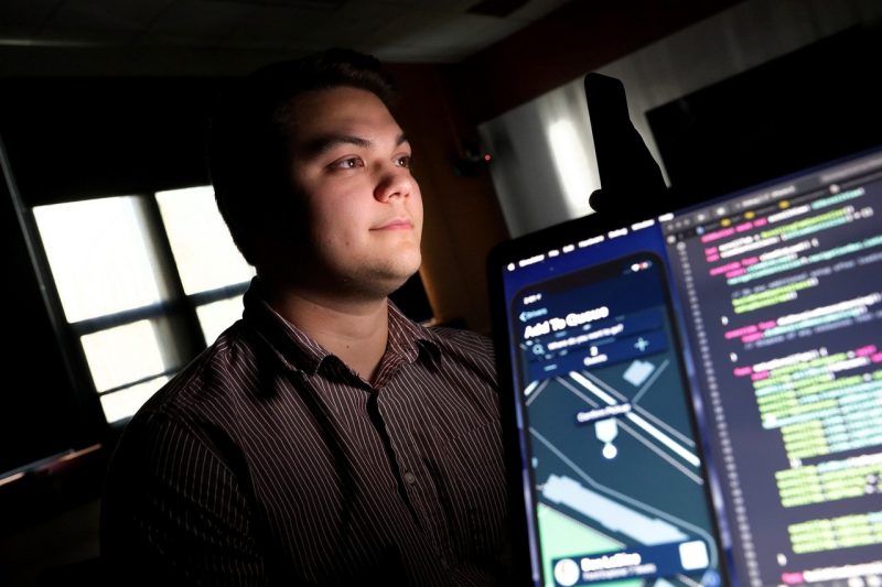 A student sits in a dark room programming on his computer.