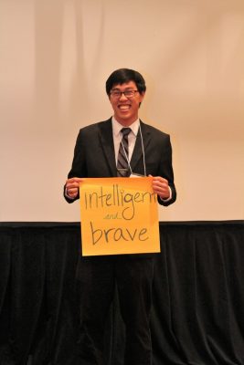 Carlin Sun holds up sign with the words "intelligent and brave" on it.