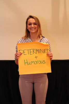 Emily Burke holds up sign with the words "determined and humorous" on it.