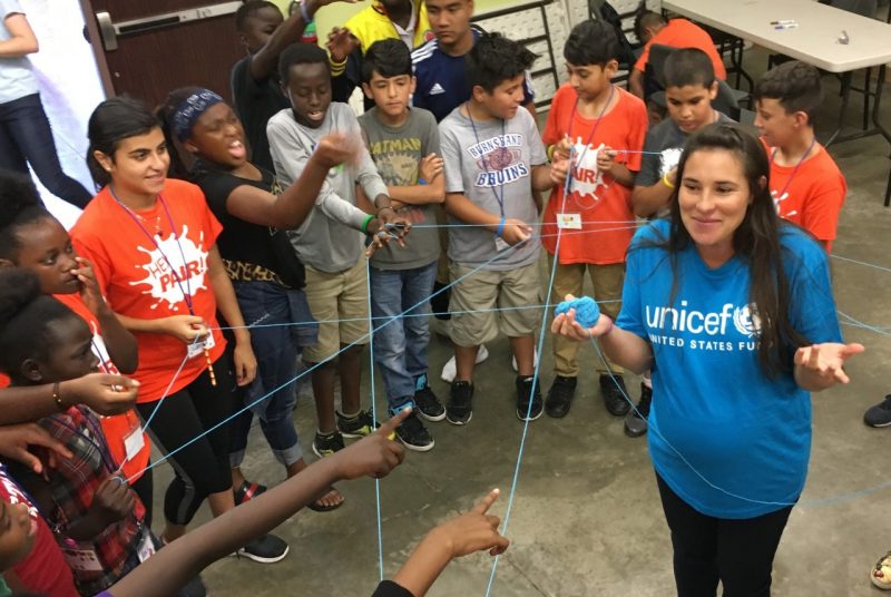 UNICEF Global Citizen Fellow Olivera Jankovska stands in the center of a circle of refugee children.